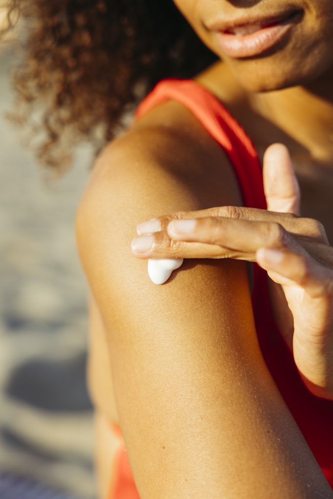 Frau cremt sich mit Sonnencreme ein